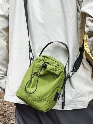 Green nylon drawstring shoulder bag with black strap and zipper pulls.
