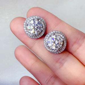 Halo diamond cluster stud earrings in silver with a central stone surrounded by smaller stones.