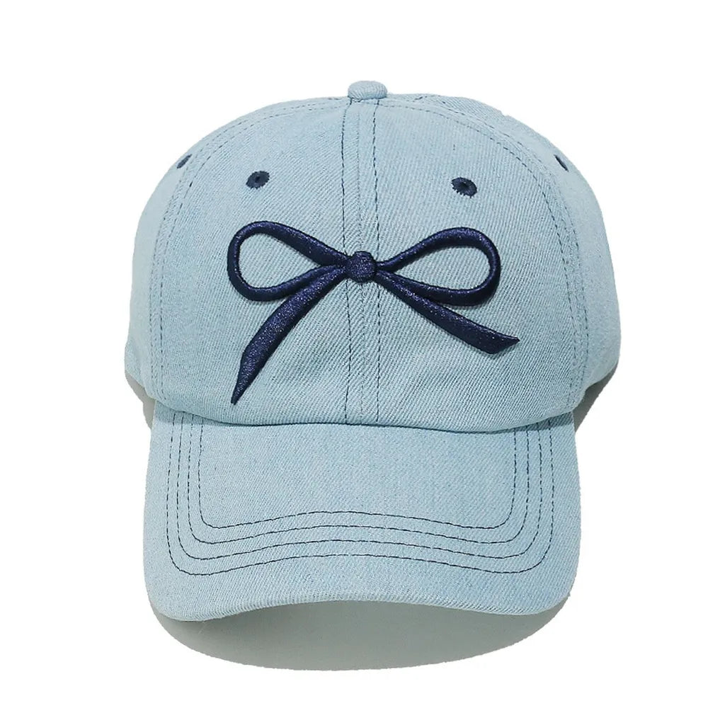 Light blue denim baseball cap with embroidered navy bow detail
