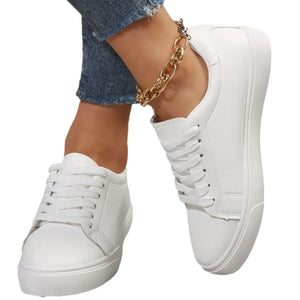 White leather-look platform sneakers with lace-up closure and gold chain anklet.
