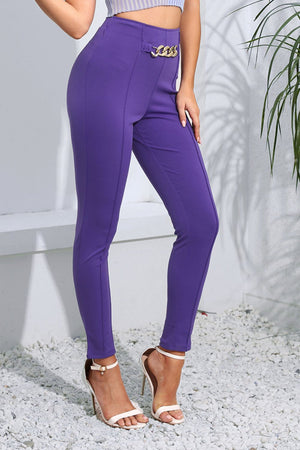 Electric purple skinny trousers with gold chain detail at the waist.