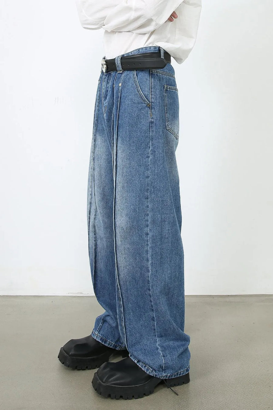 Medium wash denim trousers with prominent vertical seams and a wide leg