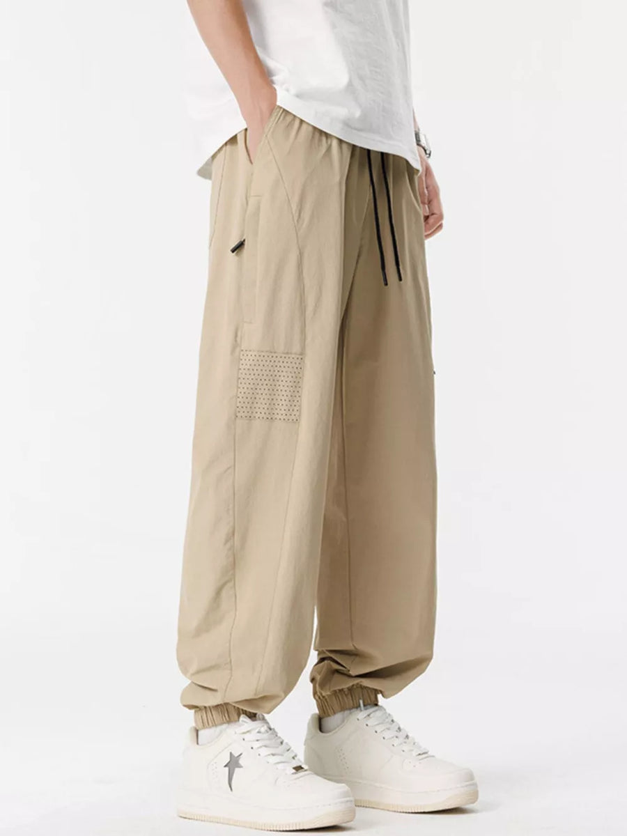 Khaki jogger sweatpants with drawstring and perforated detail on leg