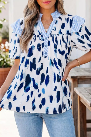 Vibrant abstract print polyester shirt with ruffled V-neck and button detail.
