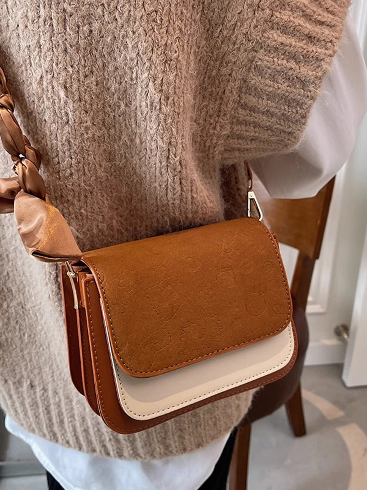 Mini two-tone crossbody bag in brown and beige with embossed pattern and braided strap.