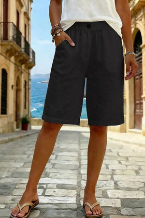 Black pocketed knee-length denim shorts with a button closure and elastic waistband.