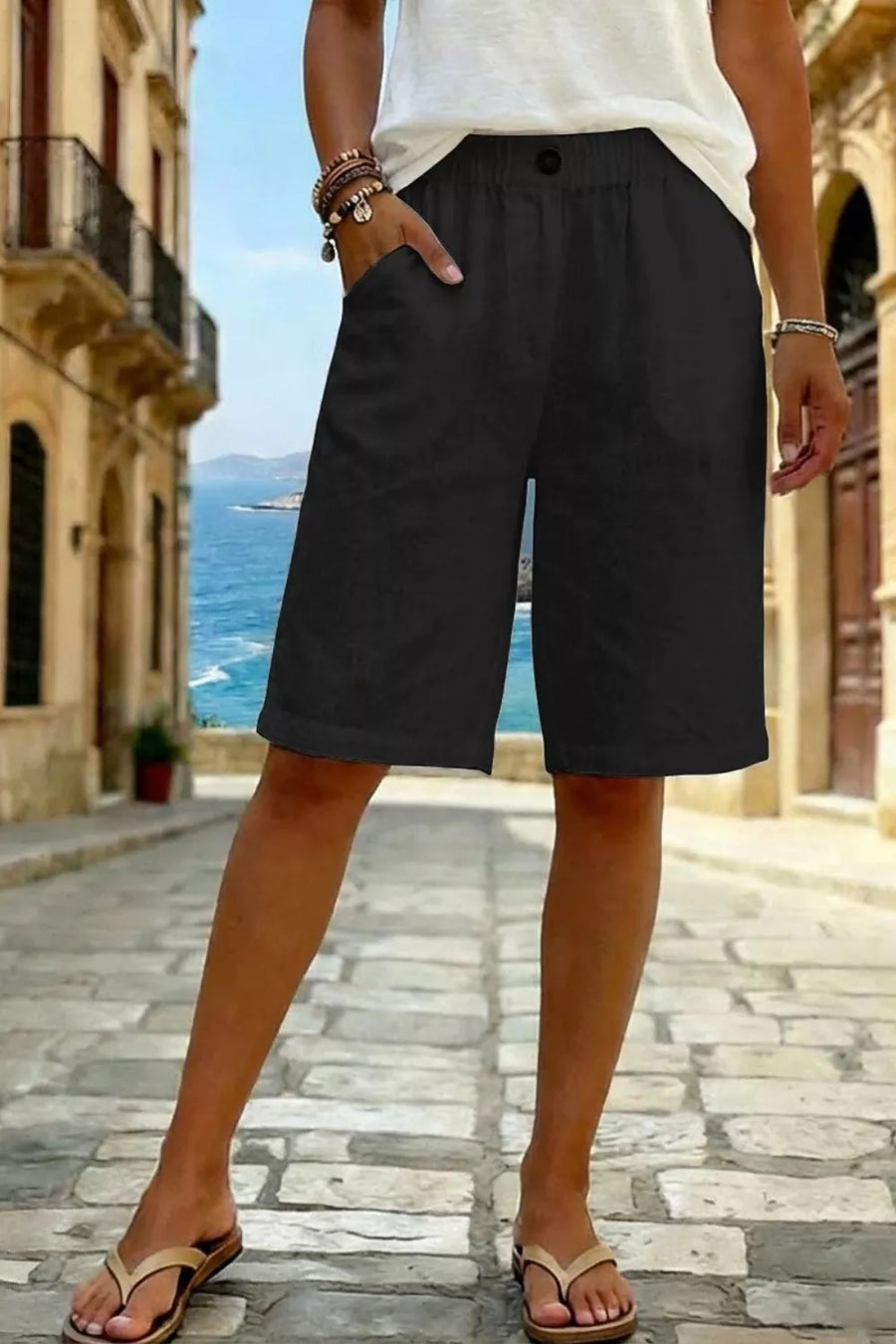Black pocketed knee-length denim shorts with a button closure and elastic waistband.