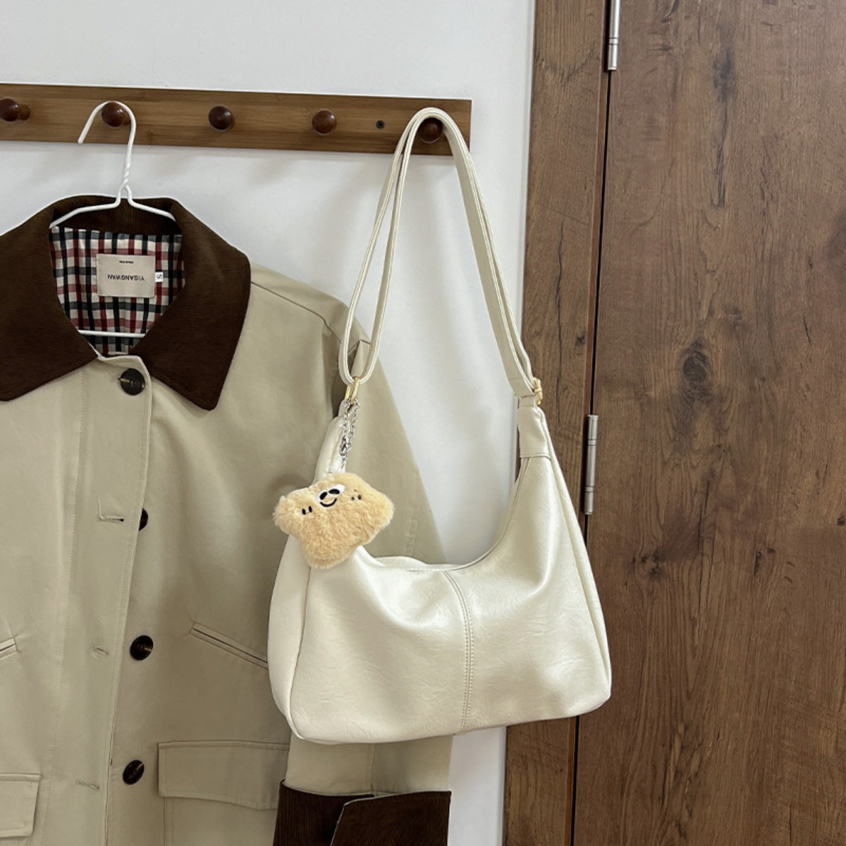 White crescent shoulder bag in pu leather with a fluffy charm and adjustable strap.
