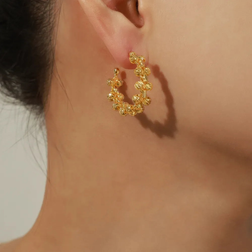 Gold textured orb C-hoop earrings with intricate bead detailing.