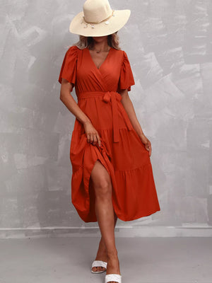 Orange-red tiered midi dress with flutter sleeves, V-neck, and belted waist.