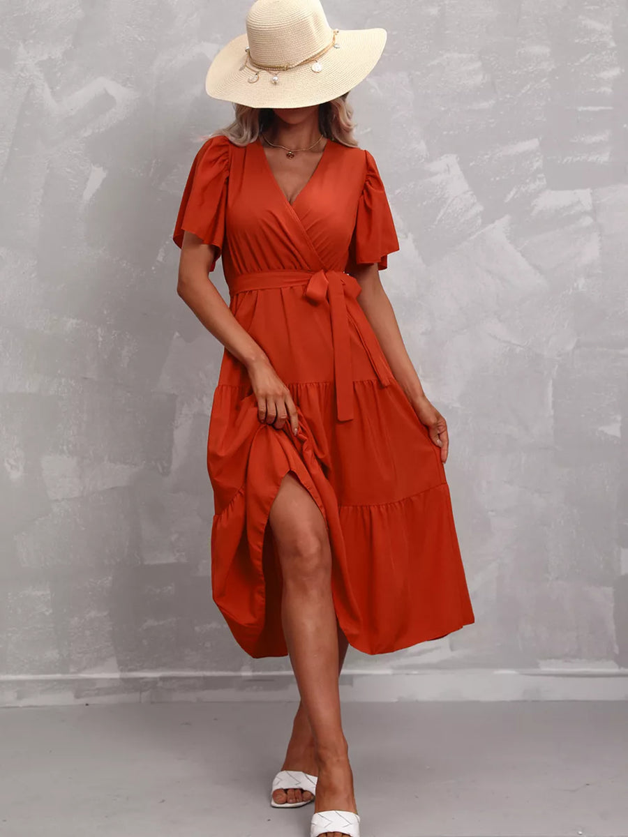Orange-red tiered midi dress with flutter sleeves, V-neck, and belted waist.