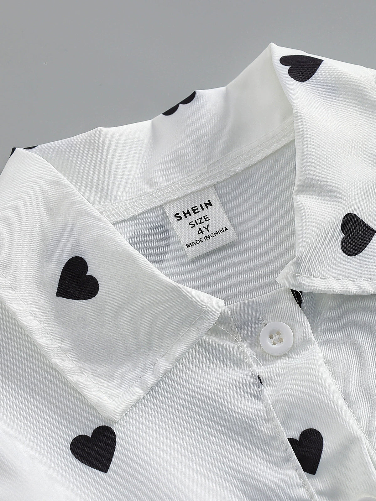 Baby dress with black heart print on white, button front detail.