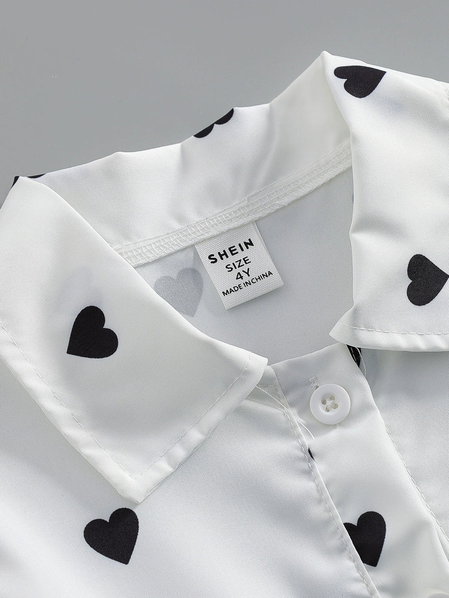 Baby dress with black heart print on white, button front detail.