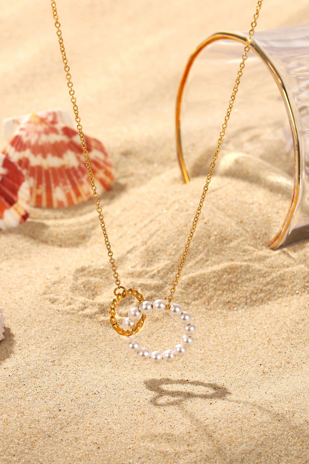 Gold-plated necklace with interlocking pearl and twisted gold circles pendant.