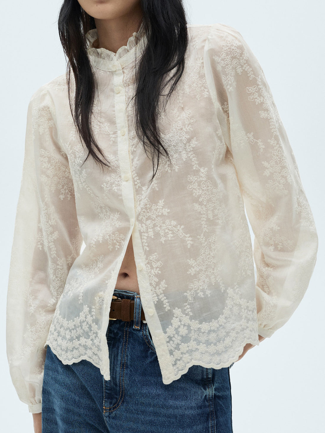 Sheer apricot button-down blouse with floral embroidery and ruffled collar.