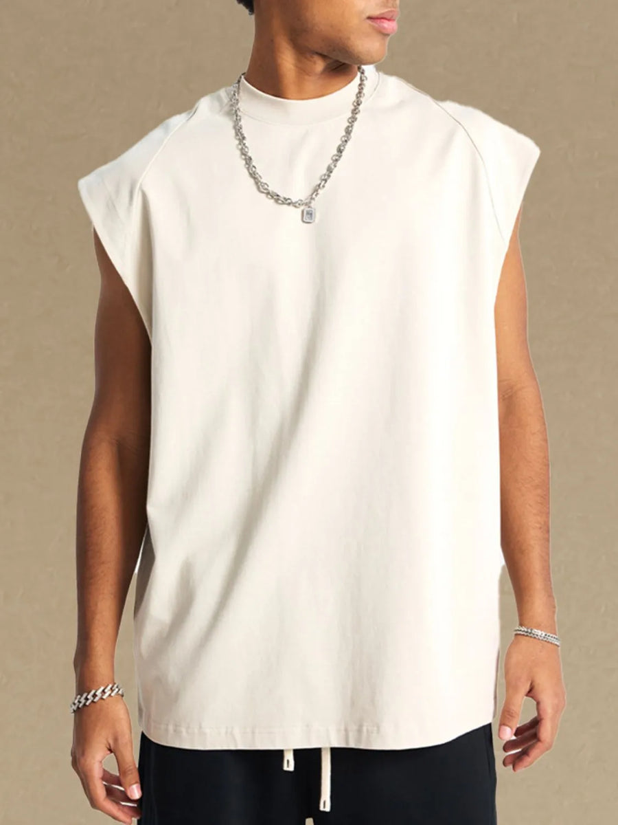 Raglan shoulder sleeveless top in beige with a mock neckline, styled with a silver chain necklace.