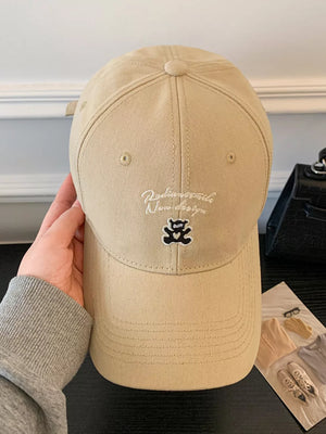 Tan baseball cap with embroidered teddy bear and text detail