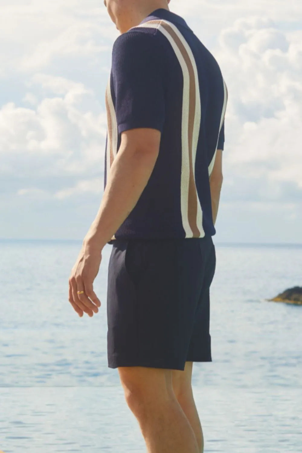 Navy knit polo shirt with vertical stripes, short sleeves, and a buttoned collar.