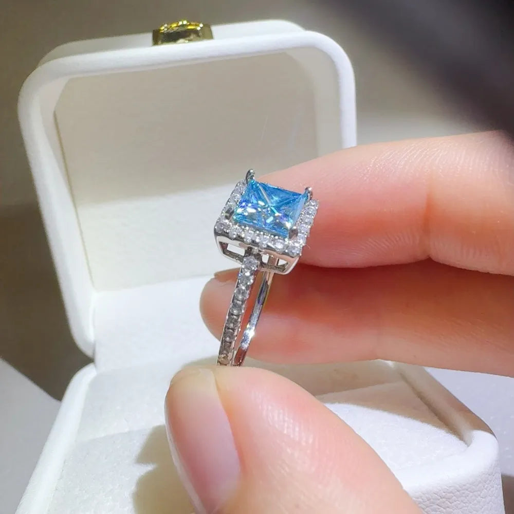 Silver ring with ice blue square halo gemstone and diamond band.