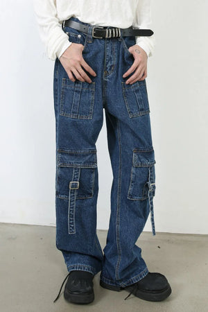 Utility denim cargo pants in medium wash with buckle strap pocket details and wide leg cut.