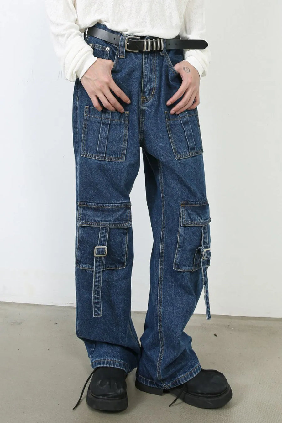 Utility denim cargo pants in medium wash with buckle strap pocket details and wide leg cut.