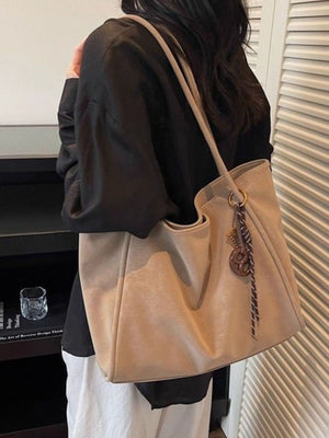 Large camel suede shoulder bag with braided rope charm and gold ring detail.