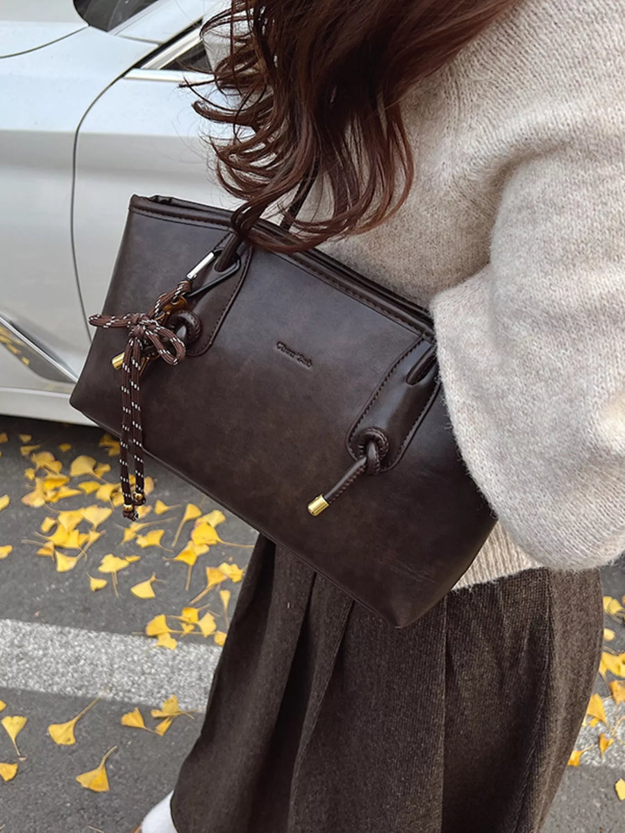 Brown leather shoulder bag with decorative rope detail and gold hardware.