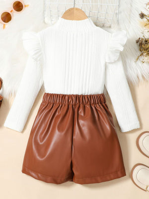 White ribbed knit top with ruffled sleeves and brown faux leather shorts.