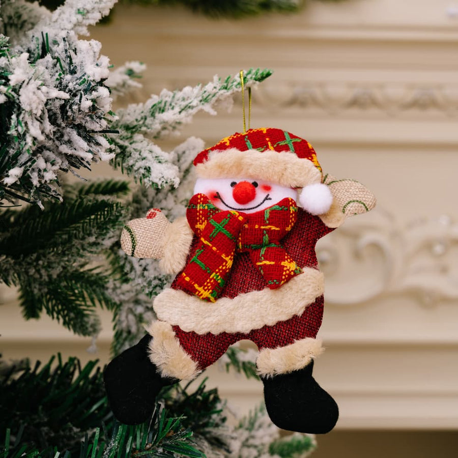 Red fabric Christmas ornament of a cheerful snowman character with a plaid scarf and hat.