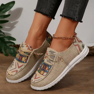 Tan canvas slip-on flats with embroidered geometric pattern and rope detail.