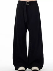 Men's black wide-leg sweatpants with belt detail and casual sneakers.