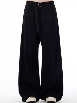 Men's black wide-leg sweatpants with belt detail and casual sneakers.