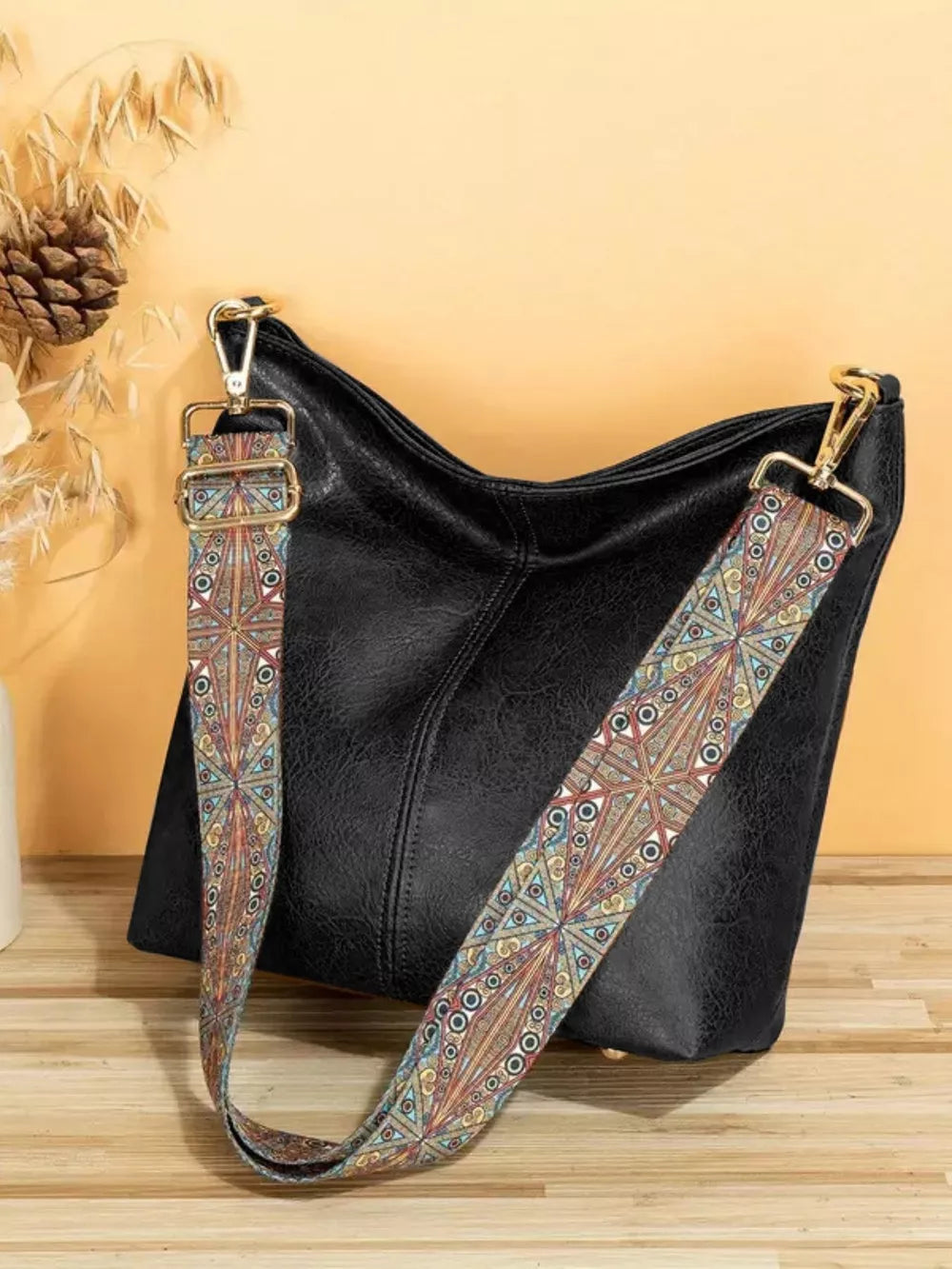Black pu leather crossbody bag with a colorful geometric strap.