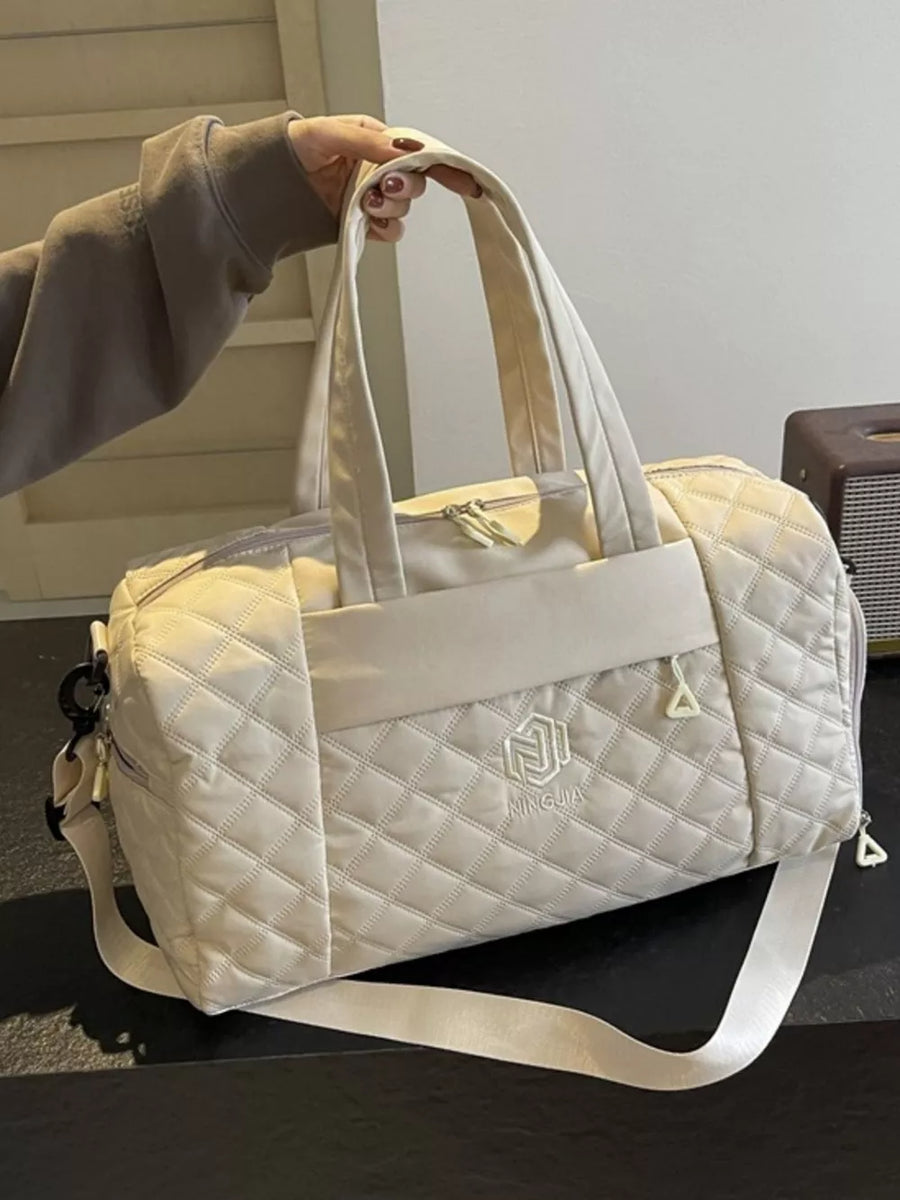 Diamond-stitched beige quilted duffel bag with adjustable strap and front logo detail.