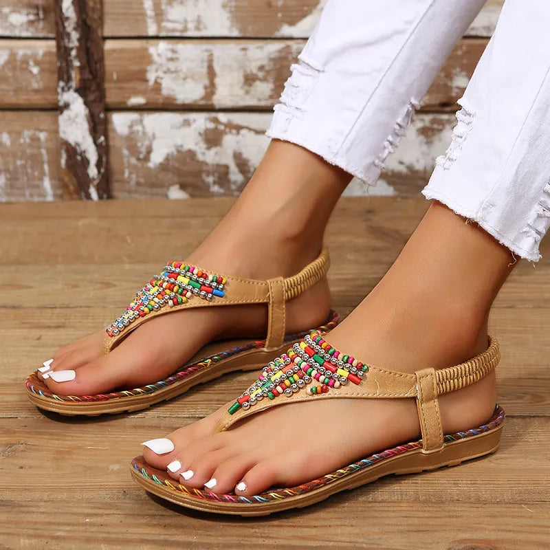 Beige thong sandals with colorful beadwork and elastic ankle strap.