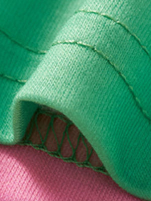 Green toddler t-shirt detail with contrast pink fabric and decorative stitching.