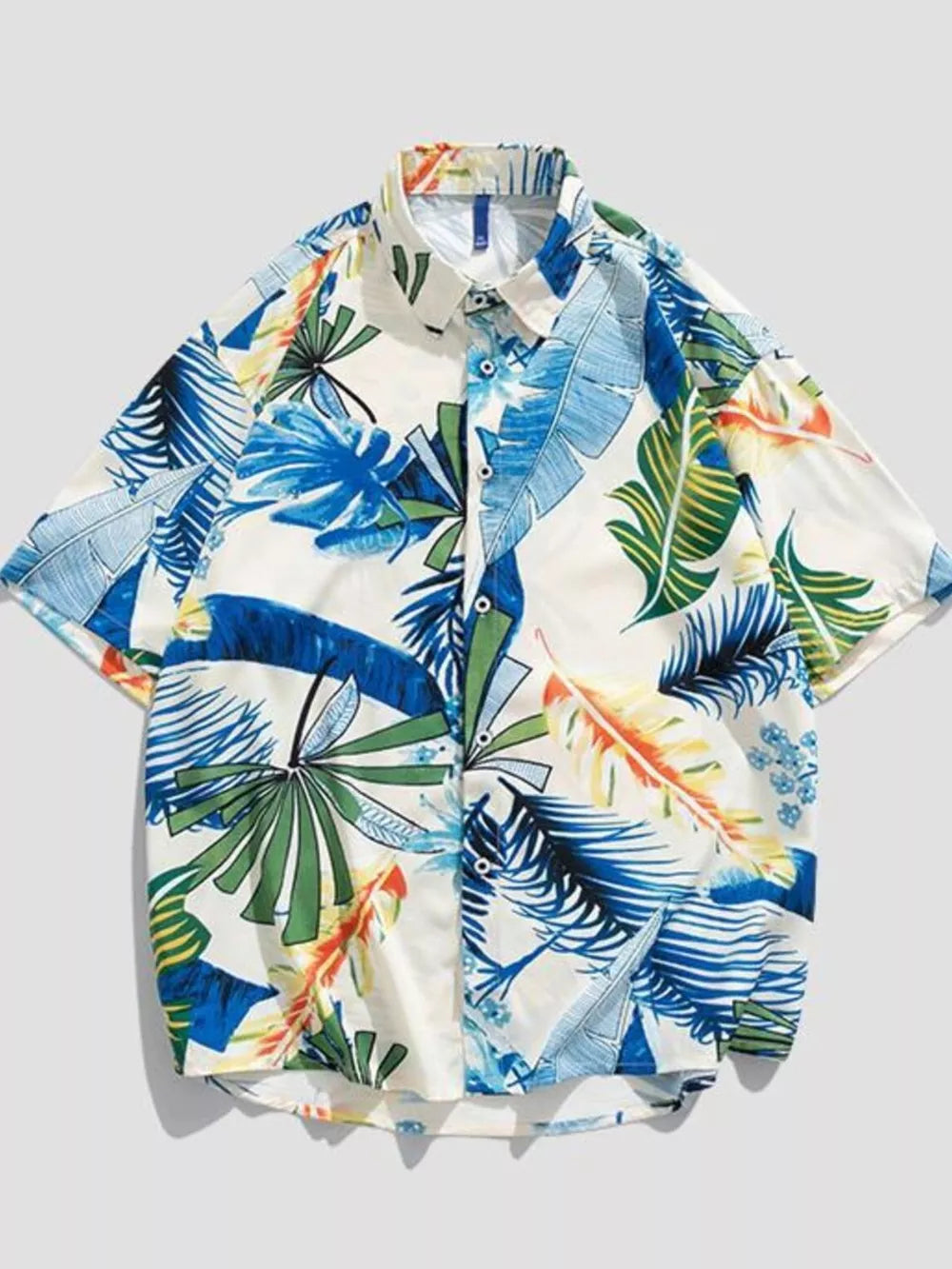 Oversized button-up shirt with tropical leaf print in blue, green, and orange on white cotton.