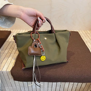 Compact nylon handbag in Khaki with brown leather accents and a smiley face charm.