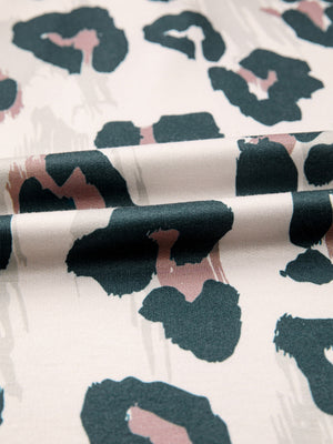 Print short sleeve blouse with abstract animal print in green, pink, and beige on white.