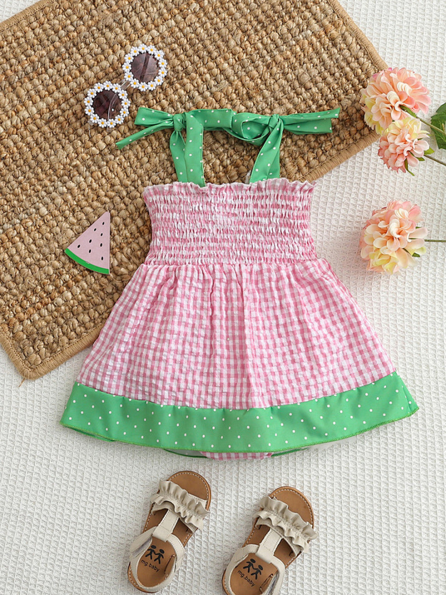 Smocked baby dress with pink gingham, green polka dot trim, and tie straps.