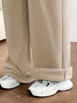 Tan wide-leg maternity joggers with cuffed hems, styled with white sneakers.