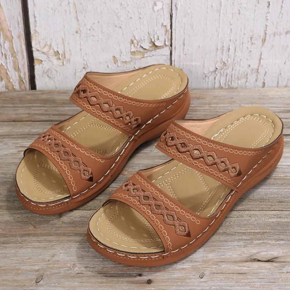 Embroidered strap comfort slides in caramel with a crisscross pattern and white stitching.