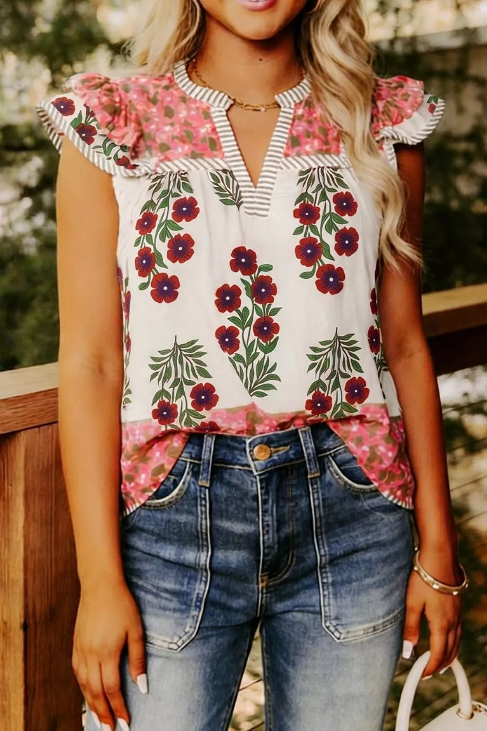 Vibrant floral cotton blouse with ruffle sleeves and keyhole neckline, paired with denim jeans.