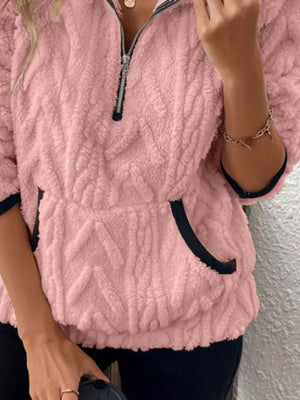 Pink sherpa half zip sweatshirt with textured pattern and black trim pockets.