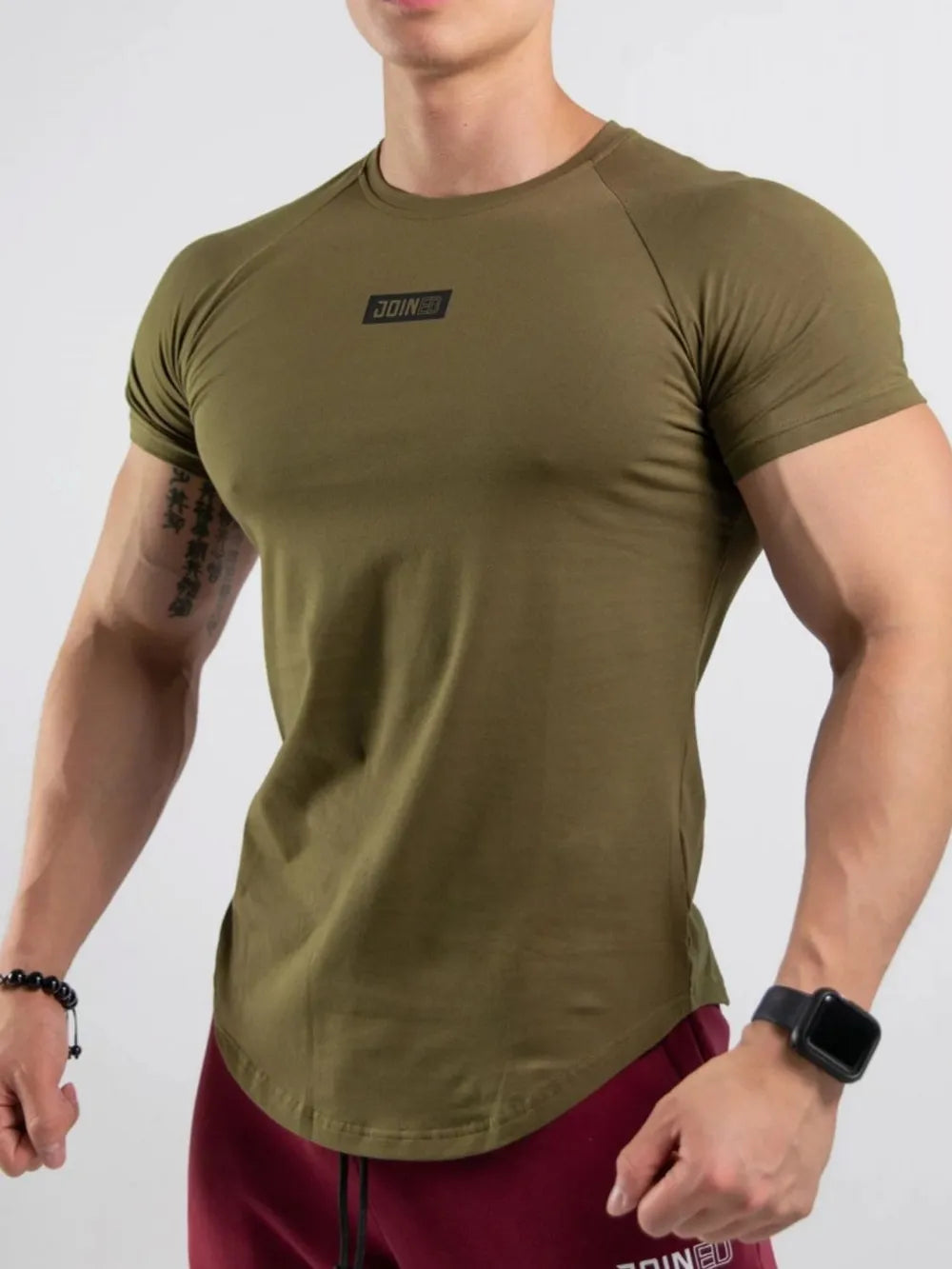 Olive performance raglan tee with black logo detail and curved hem.