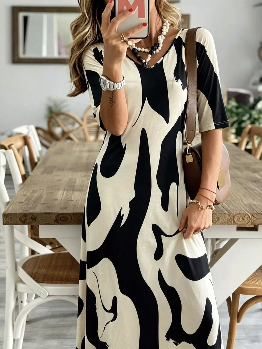 Maxi dress with abstract print, V-neck, short sleeves, and flowing skirt.