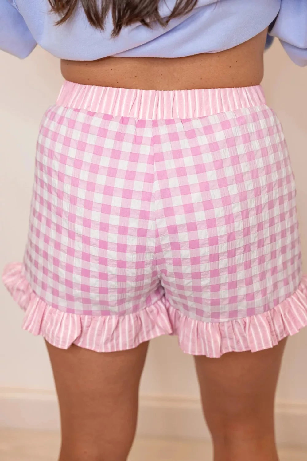 Blush pink gingham cotton shorts with ruffle hem and striped waistband.
