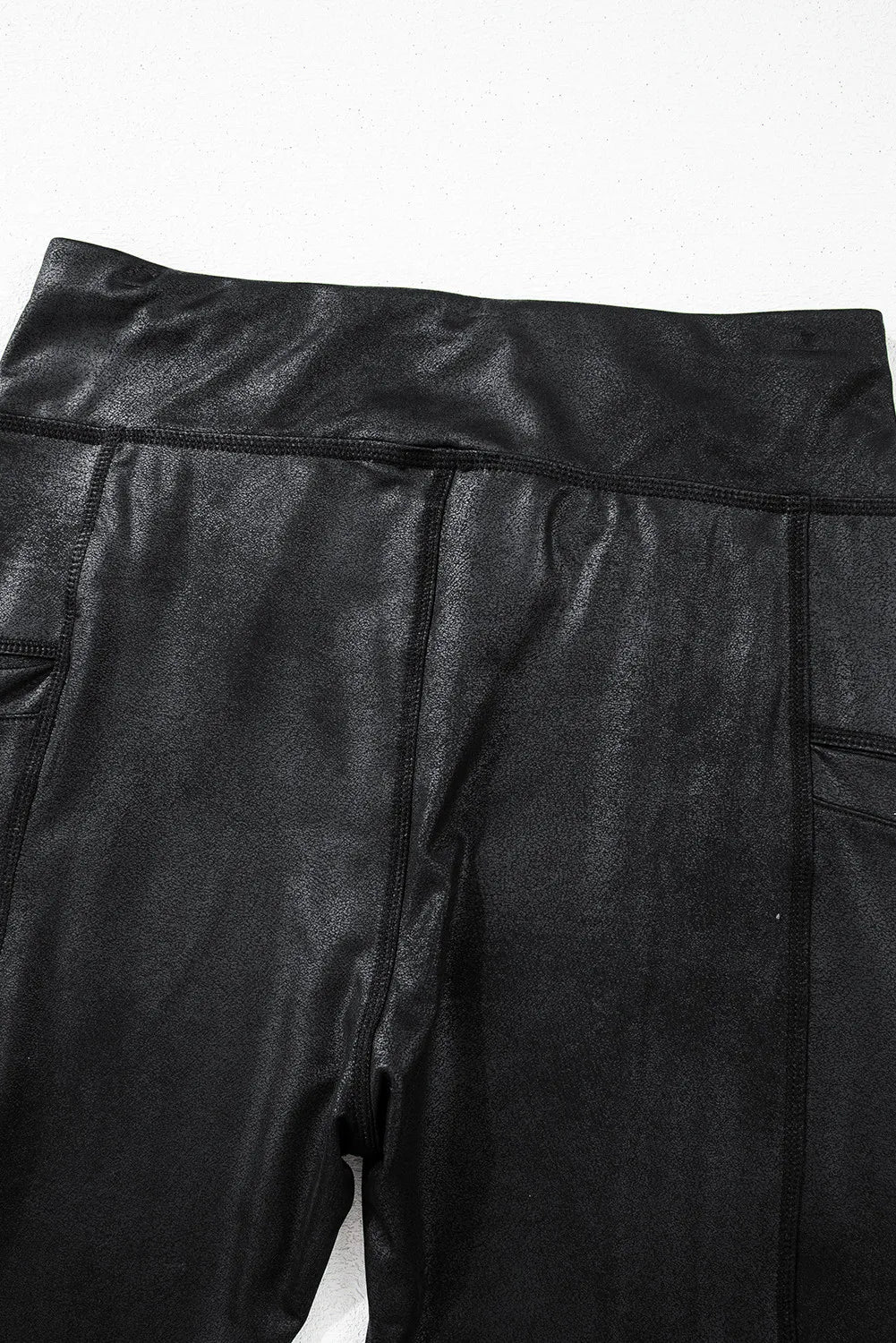 Black faux leather leggings with textured finish and side pockets.