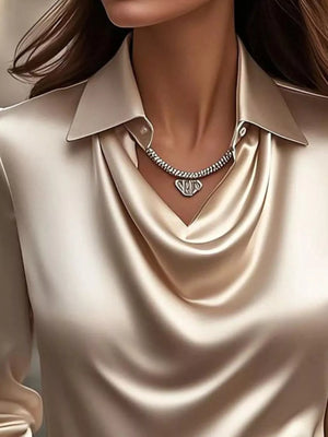 Tan satin cowl neck long-sleeve blouse with a collared neckline and draped front.