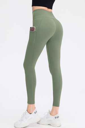 Sage green athletic leggings with phone pocket and white sneakers